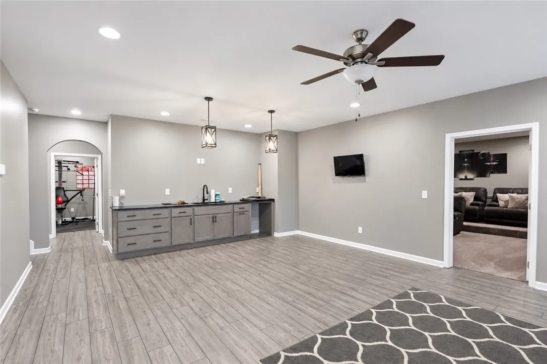 An expansive lower level recreation room includes a wet bar and modern wood-look flooring.