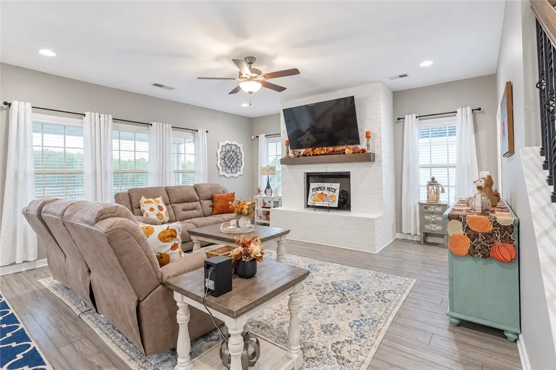 An inviting gathering space centers on a white brick fireplace alongside classic wood flooring.