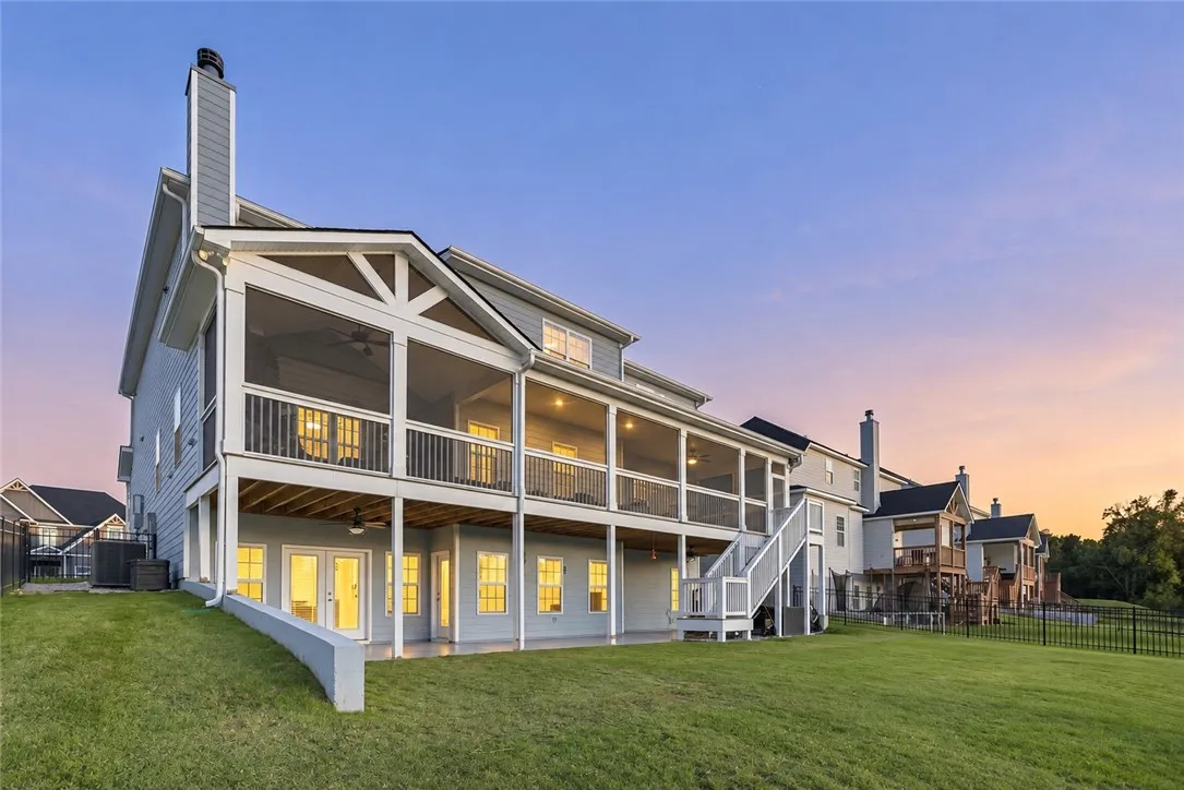 A spacious double-decker screened porch overlooks a manicured lawn under a twilight sky.