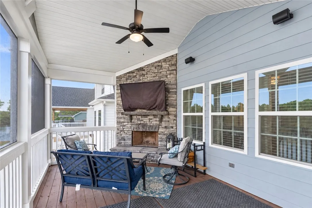 A stone fireplace adds warmth to this sheltered porch with wood decking.
