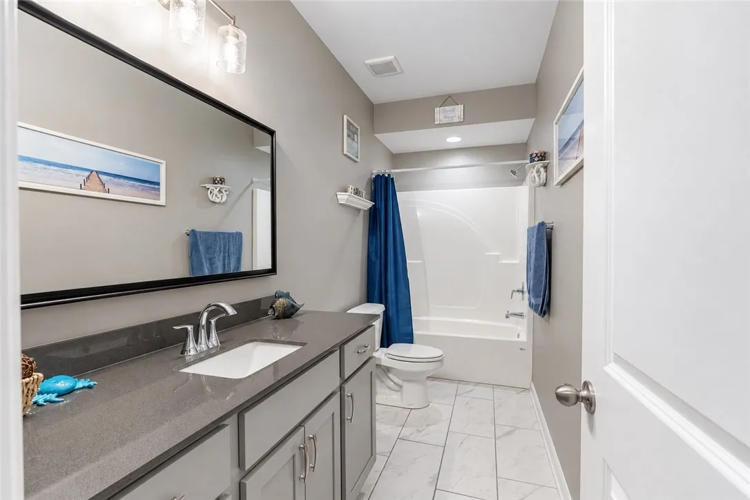 A classic tub shower combination and solid surface vanity define this sleek neutral bathroom.