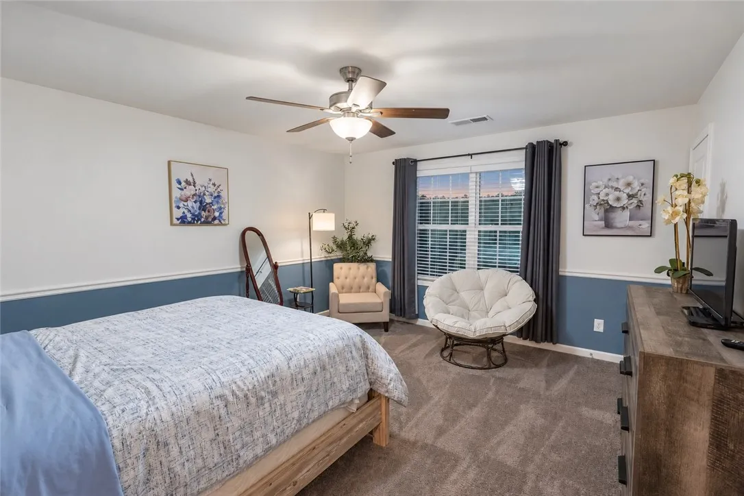 Plush carpeting anchors this bedroom under a classic tray ceiling with wainscoted wall detailing.