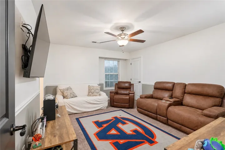A comfortable media room features crown molding and a window allowing for soft natural light.