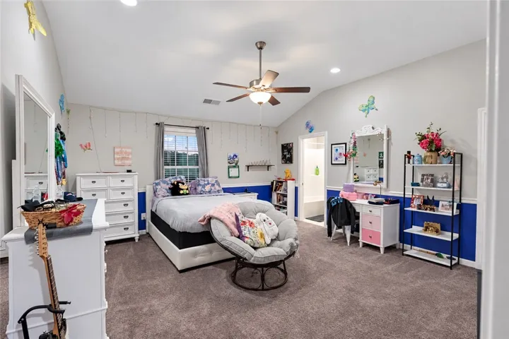 A spacious secondary bedroom features vaulted ceilings and soft carpeting underfoot.
