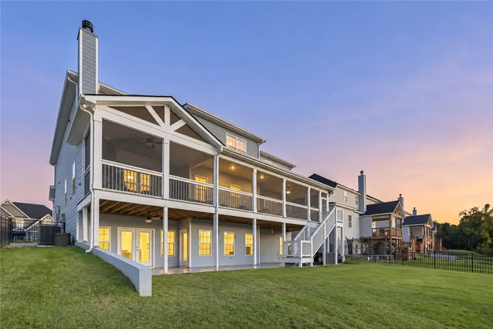 A spacious double-decker screened porch overlooks a manicured lawn under a twilight sky.