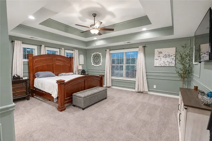 An elegant tray ceiling with molding frames this comfortable bedroom space.
