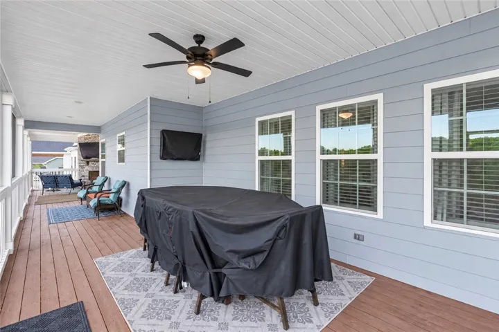 An expansive covered deck features natural wood plank flooring and clean horizontal lap siding.