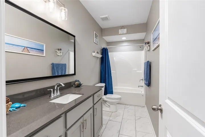 A classic tub shower combination and solid surface vanity define this sleek neutral bathroom.