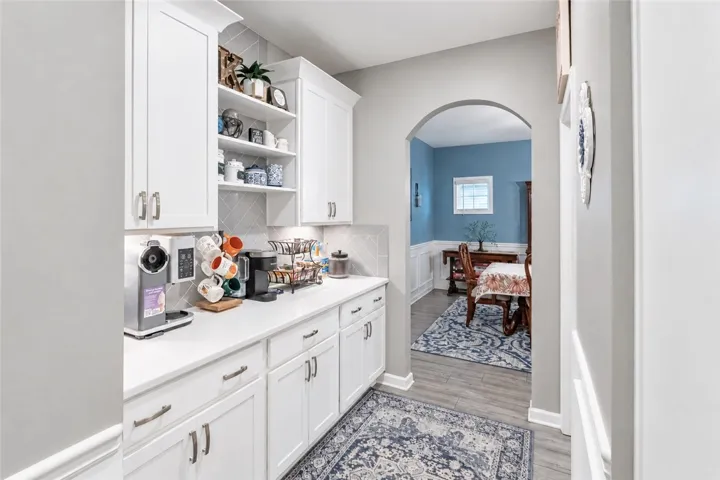 An arched doorway connects a well-appointed butler pantry to an adjacent dining space.