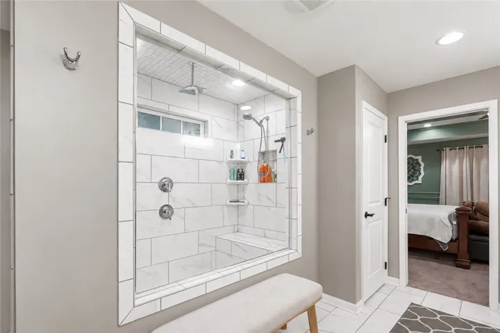 Elegant tile work surrounds a glass-enclosed walk-in shower situated adjacent to the bedroom entry.