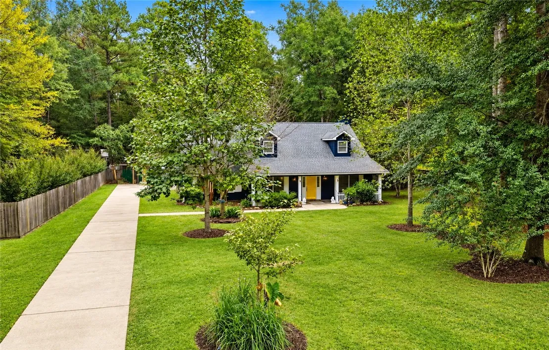 A long concrete driveway guides you through a green lawn to this classic home.