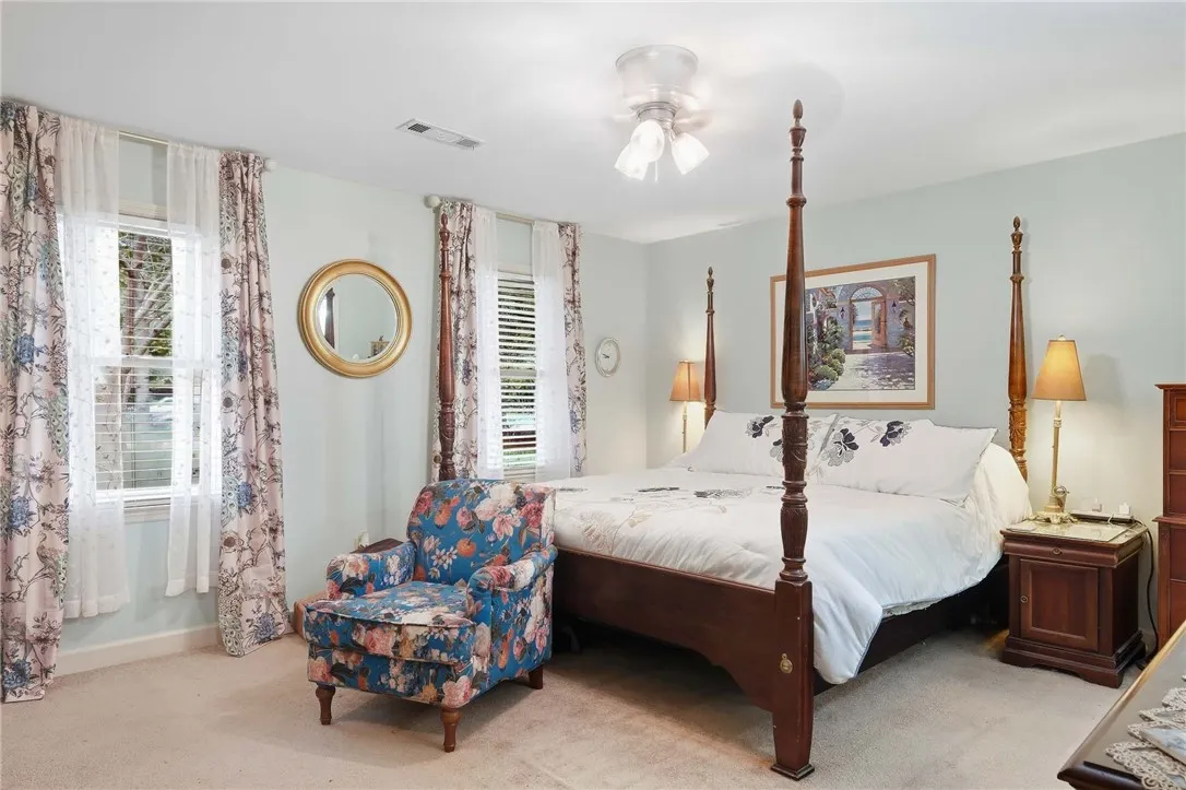 Double windows frame this classic sleeping space finished with soft carpeting and neutral walls.