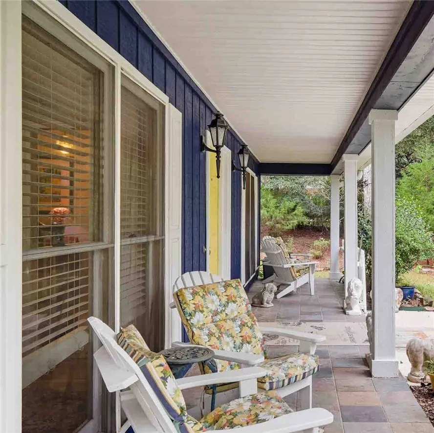 A spacious covered porch offers stone tile flooring and supportive support columns.