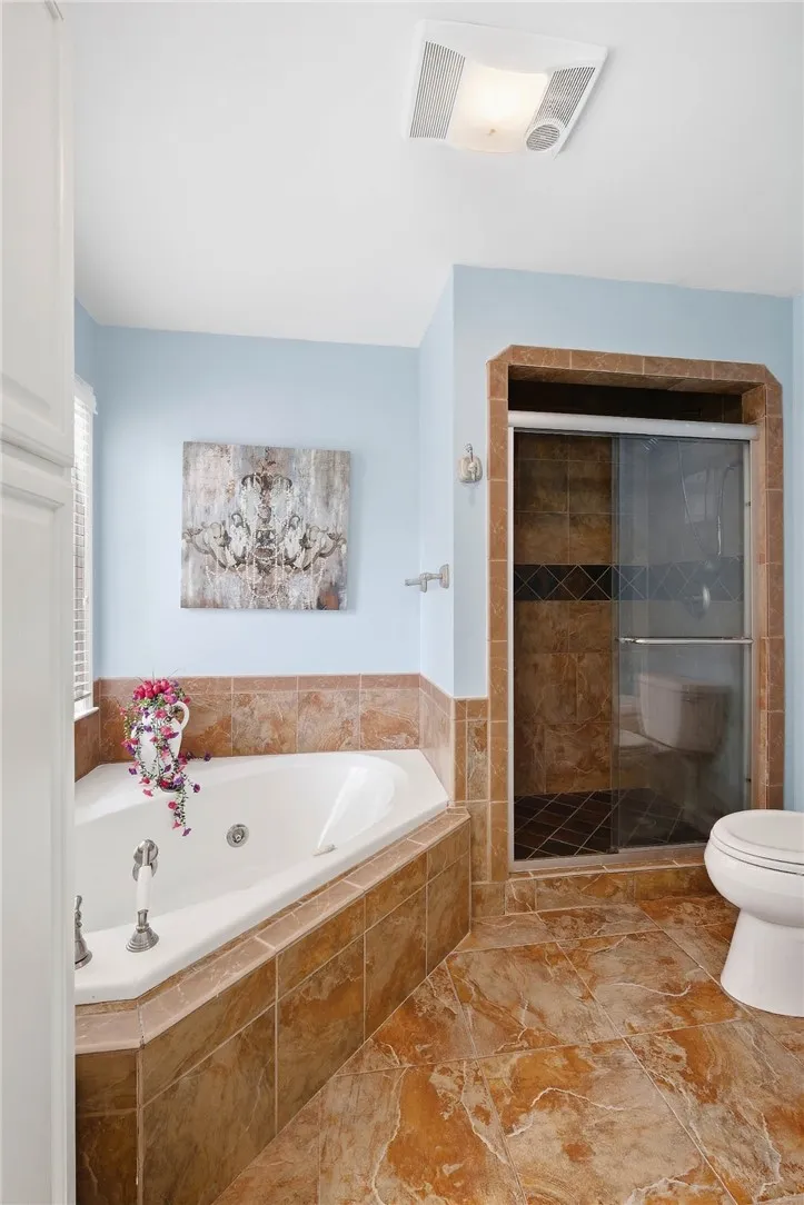 Earth-toned tiles floor this private bath featuring a corner soaking tub and walk-in shower.