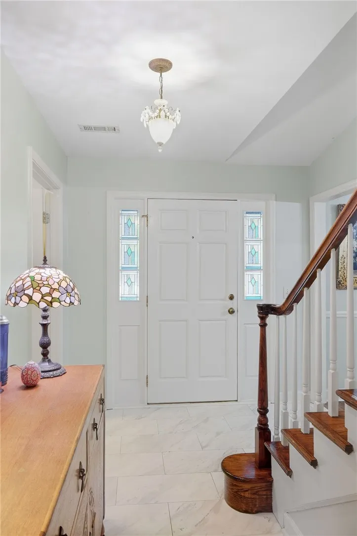 Gleaming tile floors and a classic wooden staircase define this welcoming entry foyer.