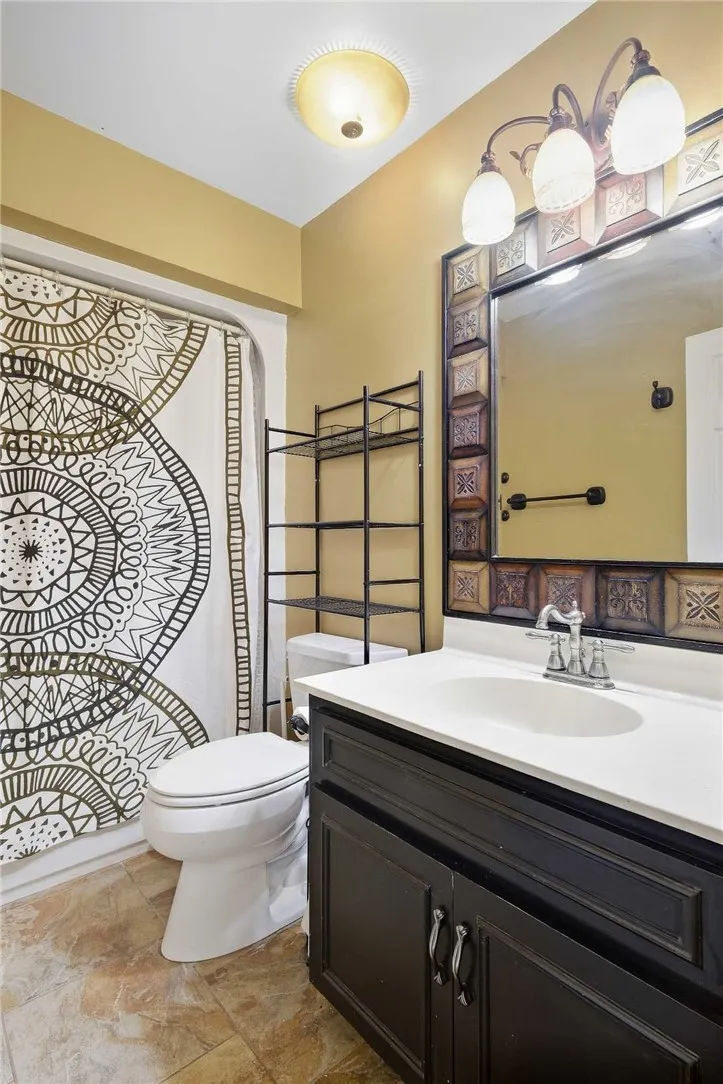 A single-sink vanity anchors this bathroom completed with textured tile flooring.