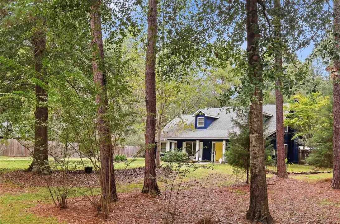 Mature trees frame the view of this charming home nestled in a private wooded setting.