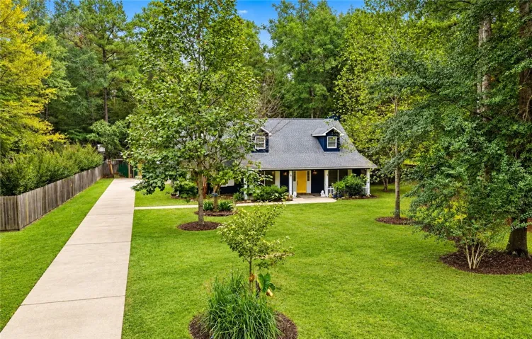 A long concrete driveway guides you through a green lawn to this classic home.