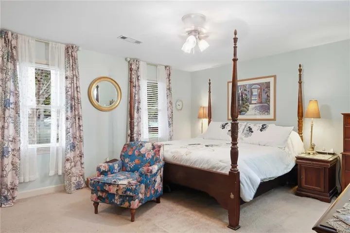 Double windows frame this classic sleeping space finished with soft carpeting and neutral walls.