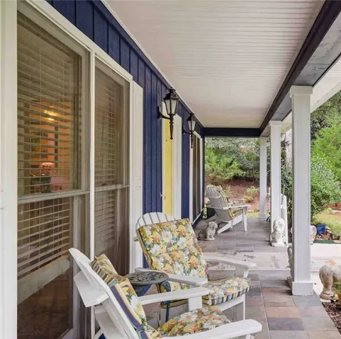 A spacious covered porch offers stone tile flooring and supportive support columns.