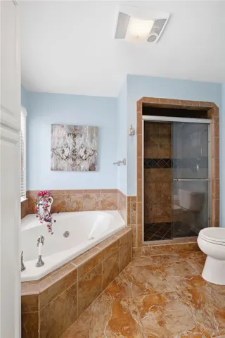 Earth-toned tiles floor this private bath featuring a corner soaking tub and walk-in shower.