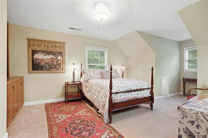 Sloped ceilings and built-in cabinetry add architectural character to this carpeted bedroom.