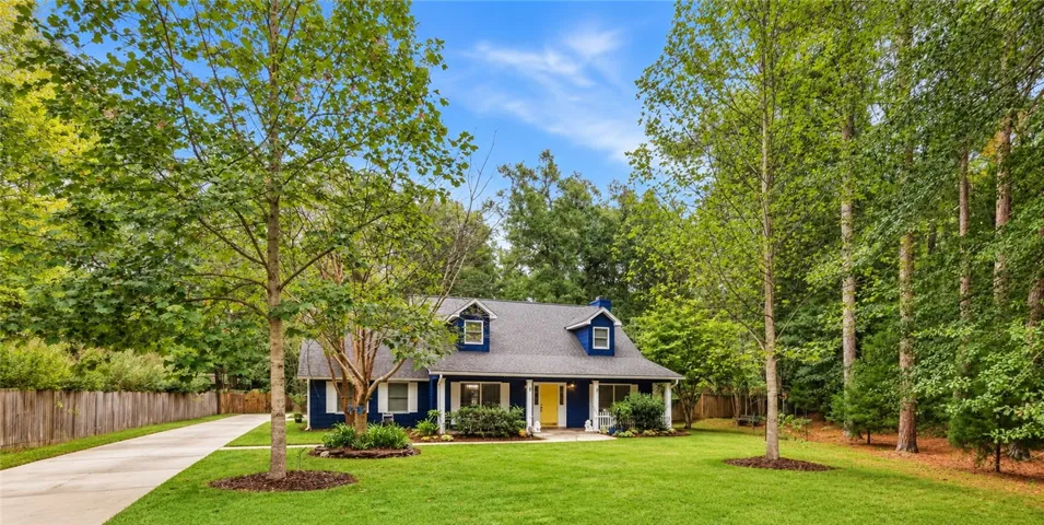 Mature trees frame a charming two-story home featuring a classic dormer-style roofline.