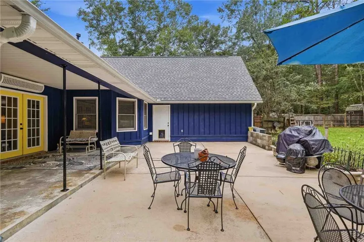 A spacious concrete patio overlooks the private backyard bordered by mature trees.