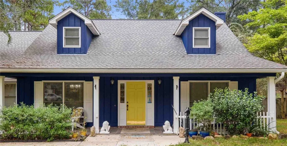 Board and batten siding meets dormer windows along a welcoming covered front porch.