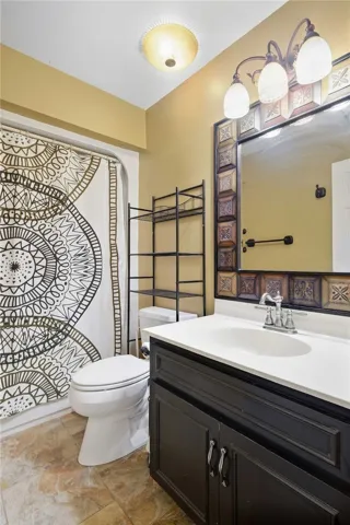 A single-sink vanity anchors this bathroom completed with textured tile flooring.