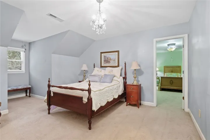 Angled ceilings and soft carpeting create a cozy atmosphere in this spacious bedroom.