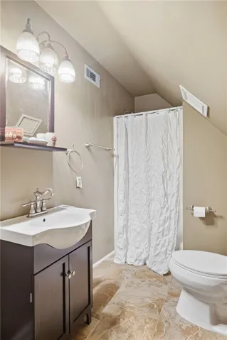 Sloped ceilings and neutral tile flooring define this charming bathroom layout.