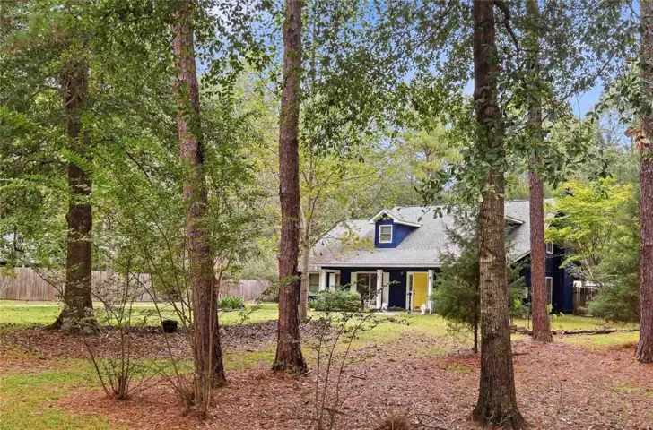 Mature trees frame the view of this charming home nestled in a private wooded setting.