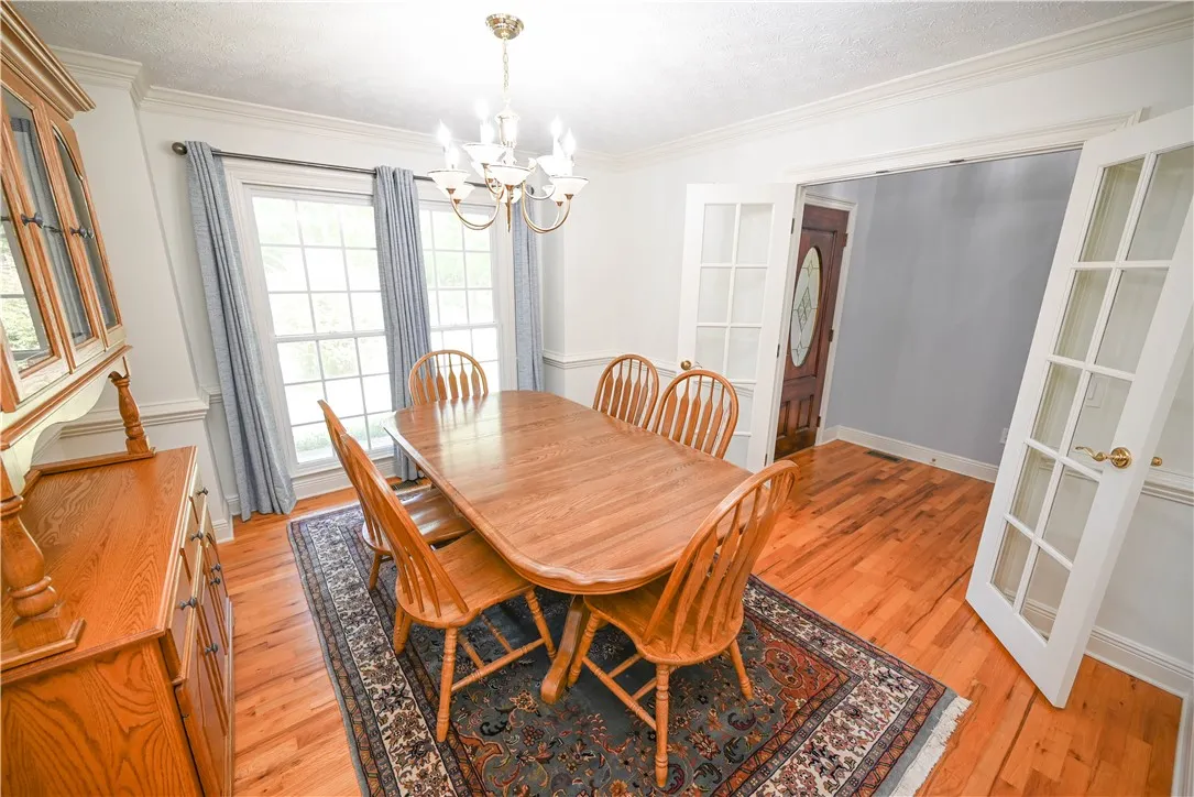 Formal dining room with big windows, elegant French doors, and chair rail detail.