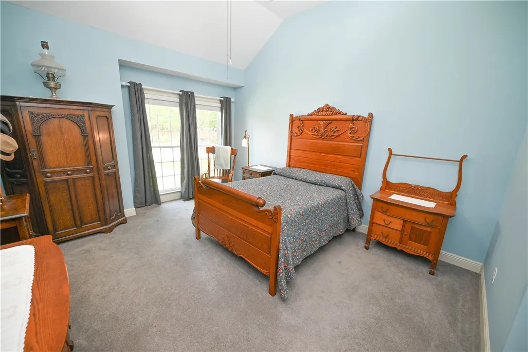 Spacious main level primary bedroom with vaulted ceiling and large windows.