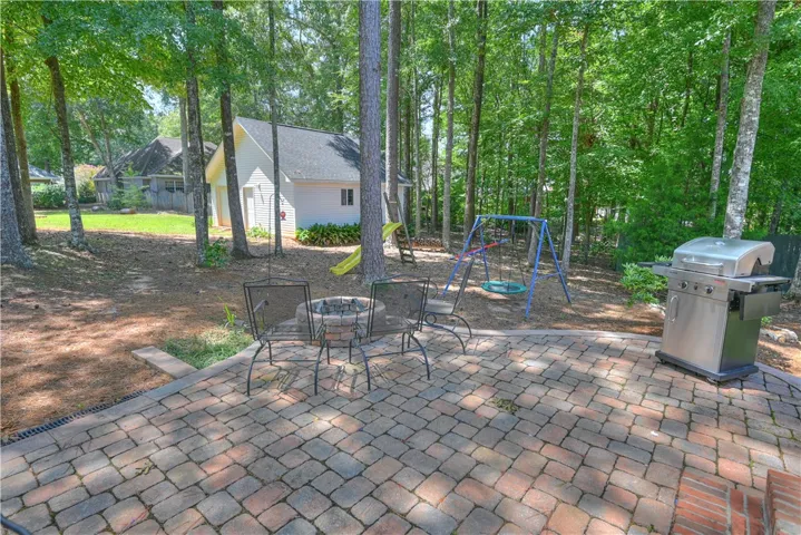 Back patio with firepit overlooking expansive yard with mature trees.