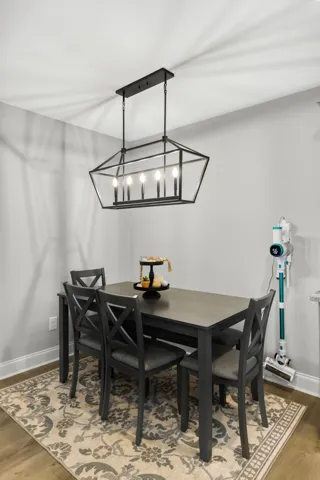 An inviting dining area features classic wood flooring and a modern linear chandelier.