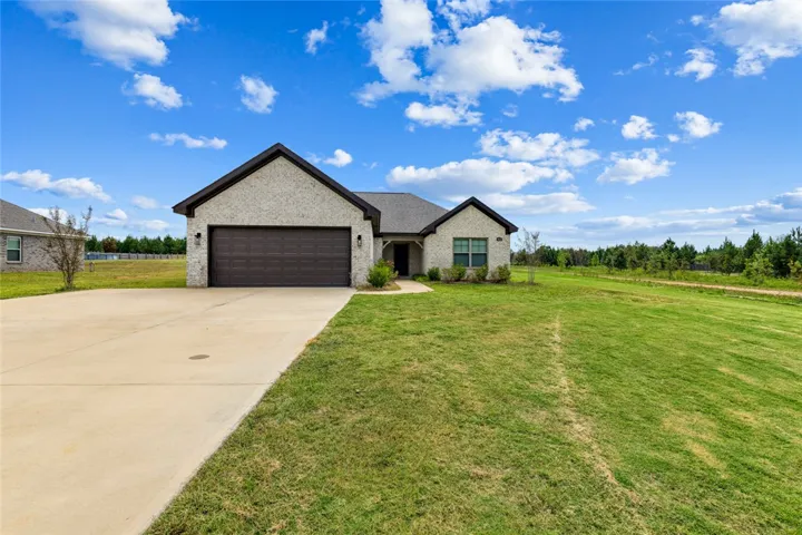 A spacious concrete driveway leads to this modern brick home situated on a manicured lawn.