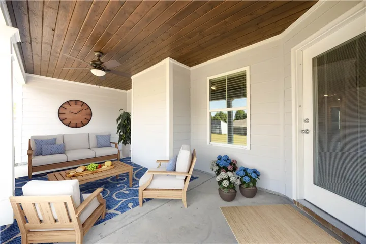 A spacious covered back porch features a warm wood-paneled ceiling and clean concrete flooring.