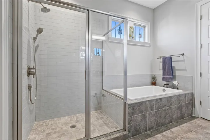 An inviting soaking tub pairs beautifully with a glass-enclosed walk-in shower.