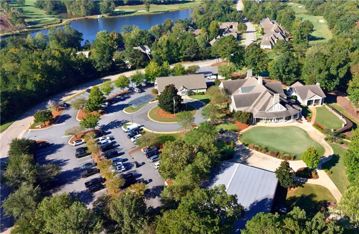 Lush fairways and a serene waterfront frame this aerial view of the neighborhood clubhouse.