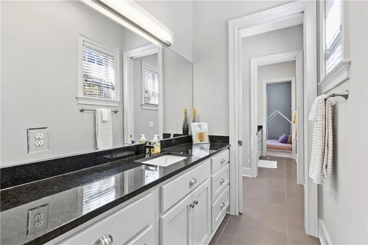 Polished stone countertops and high ceilings define this sleek, light-filled bathroom space.