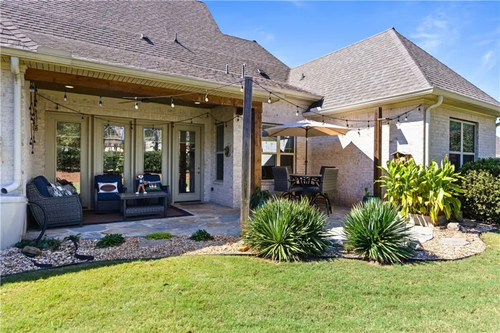 A spacious stone patio sits beneath a covered porch extension on this brick home.