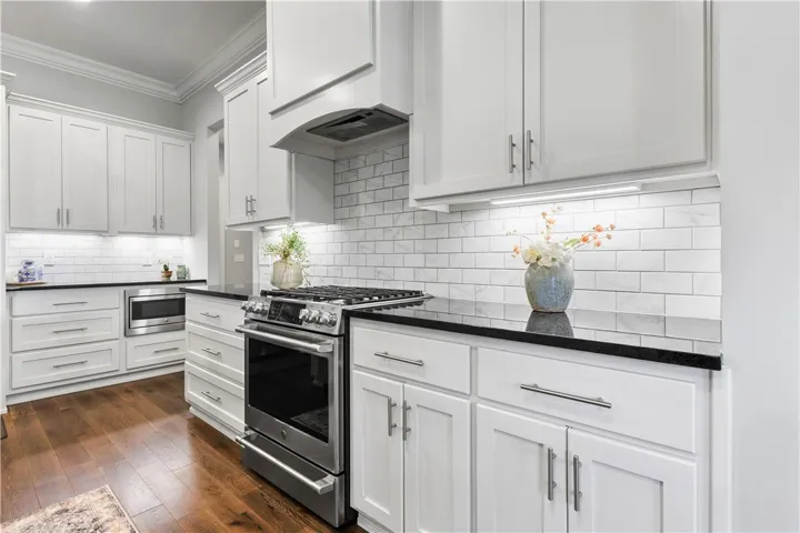 Rich hardwood flooring complements custom white cabinetry and premium stone countertops.