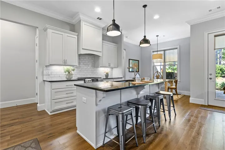 Rich hardwood floors complement shaker cabinetry and a granite-topped island in this culinary space.