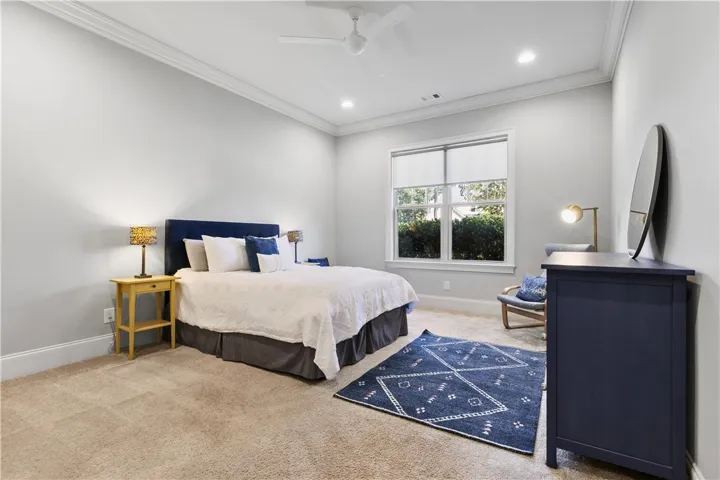 Plentiful natural light fills this bedroom featuring crown molding and recessed lighting.