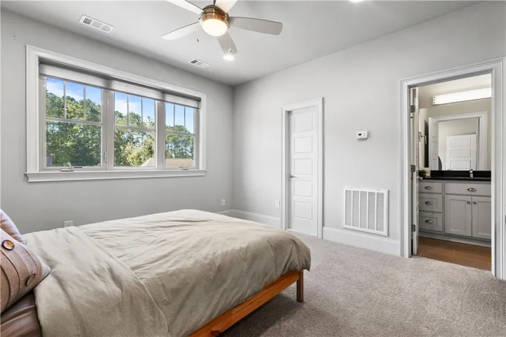 A spacious secondary bedroom features soft carpeting and convenient access to an adjacent bathroom.