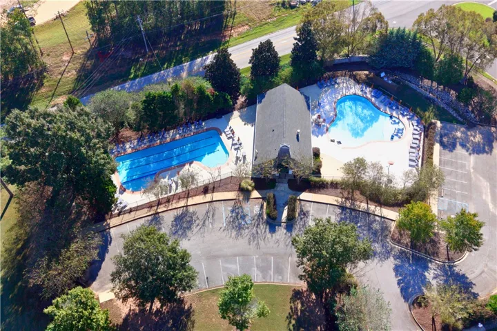 An aerial perspective showcases the community pool complex with ample parking and surrounding trees.