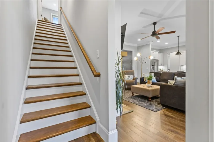 Rich hardwood stairs ascend gracefully alongside an inviting, open-concept living area with matching wood floors.