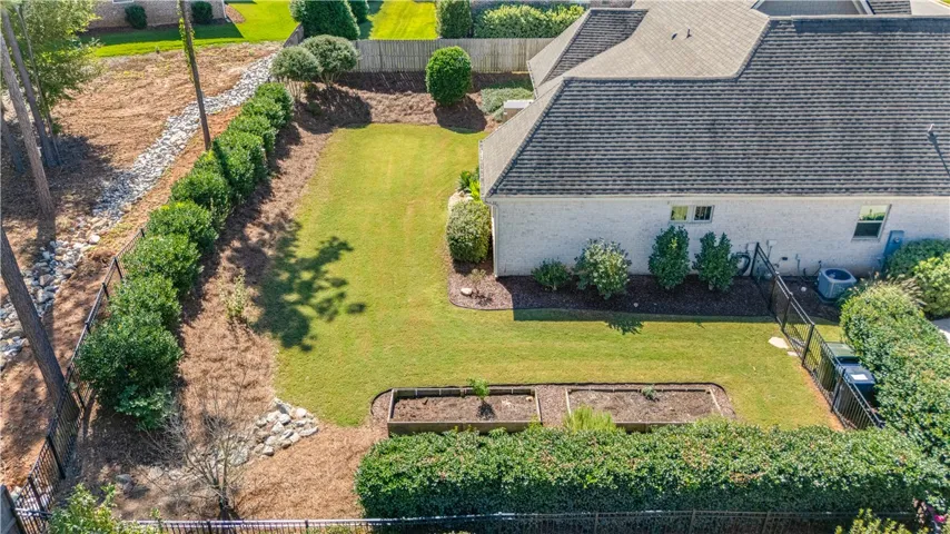 Manicured lawn space is enclosed by secure fencing and framed by mature border landscaping & wooded garden beds.